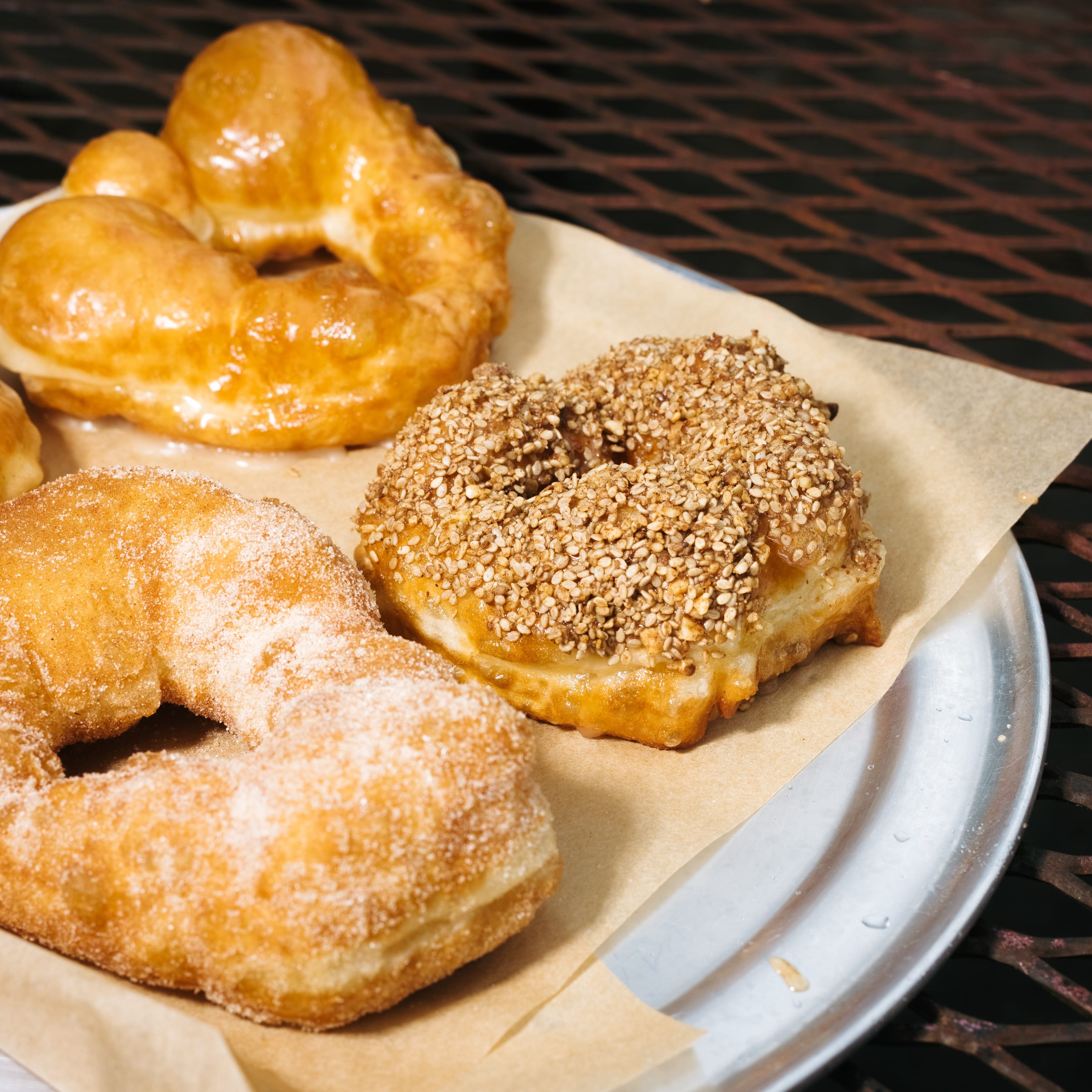 A silver platter holding three doughnuts with different toppings.